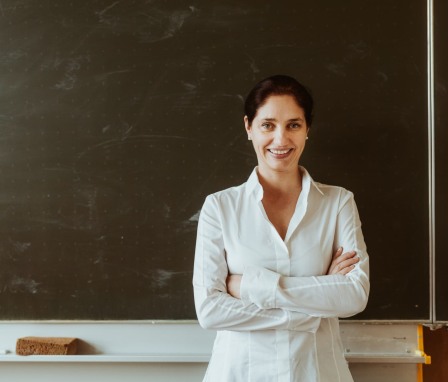 Smiling female teacher standing in front a chalkboard